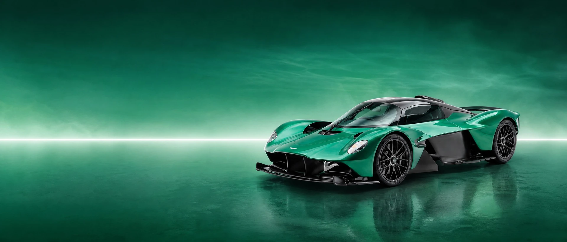 A green Aston Martin Valkyrie, front three-quarter view on an emerald field with a rising line of light