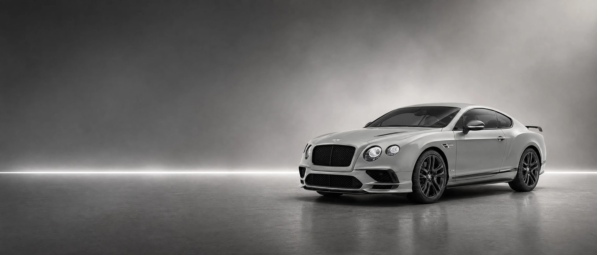 A silver-grey Bentley Continental Supersports, front three-quarter view on a graphite field with a taut seam of light