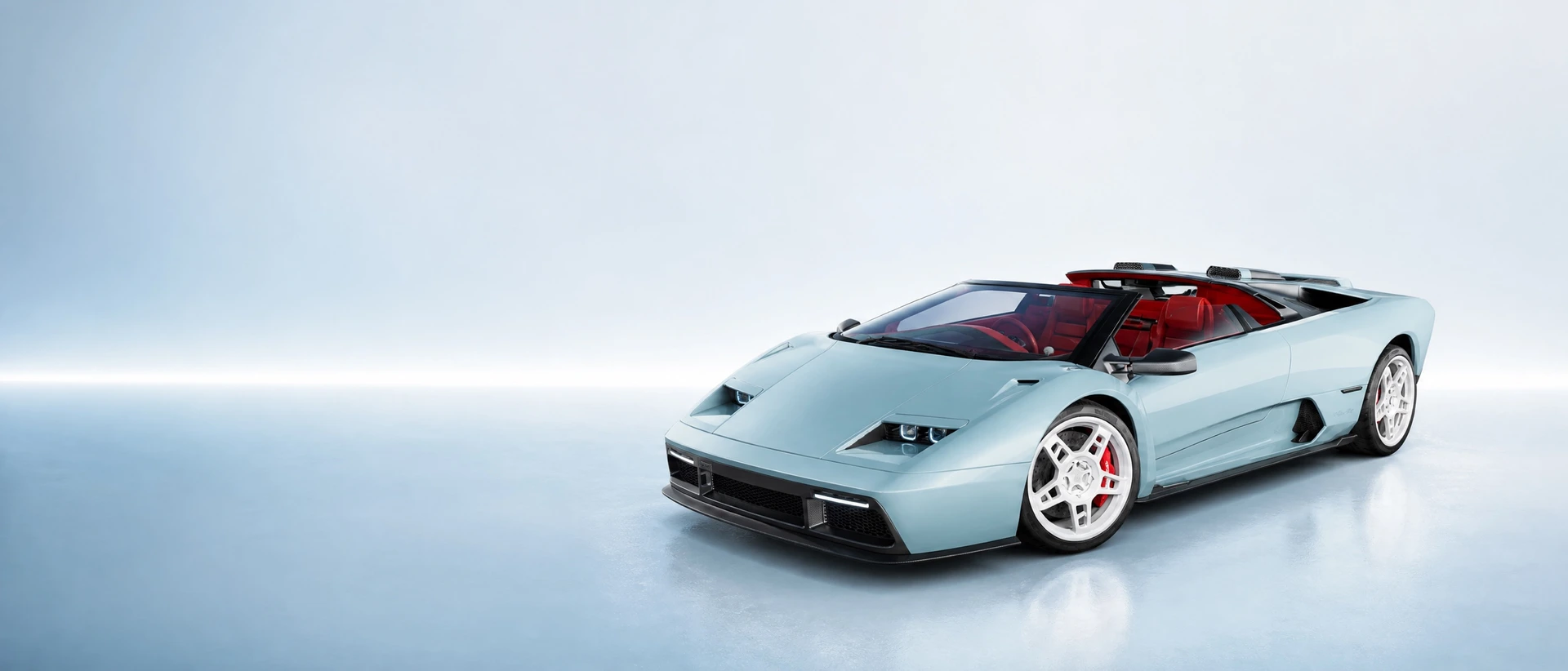 Eccentrica V12 Roadster in pale glacier blue with red interior, front three-quarter view on a pale blue stage