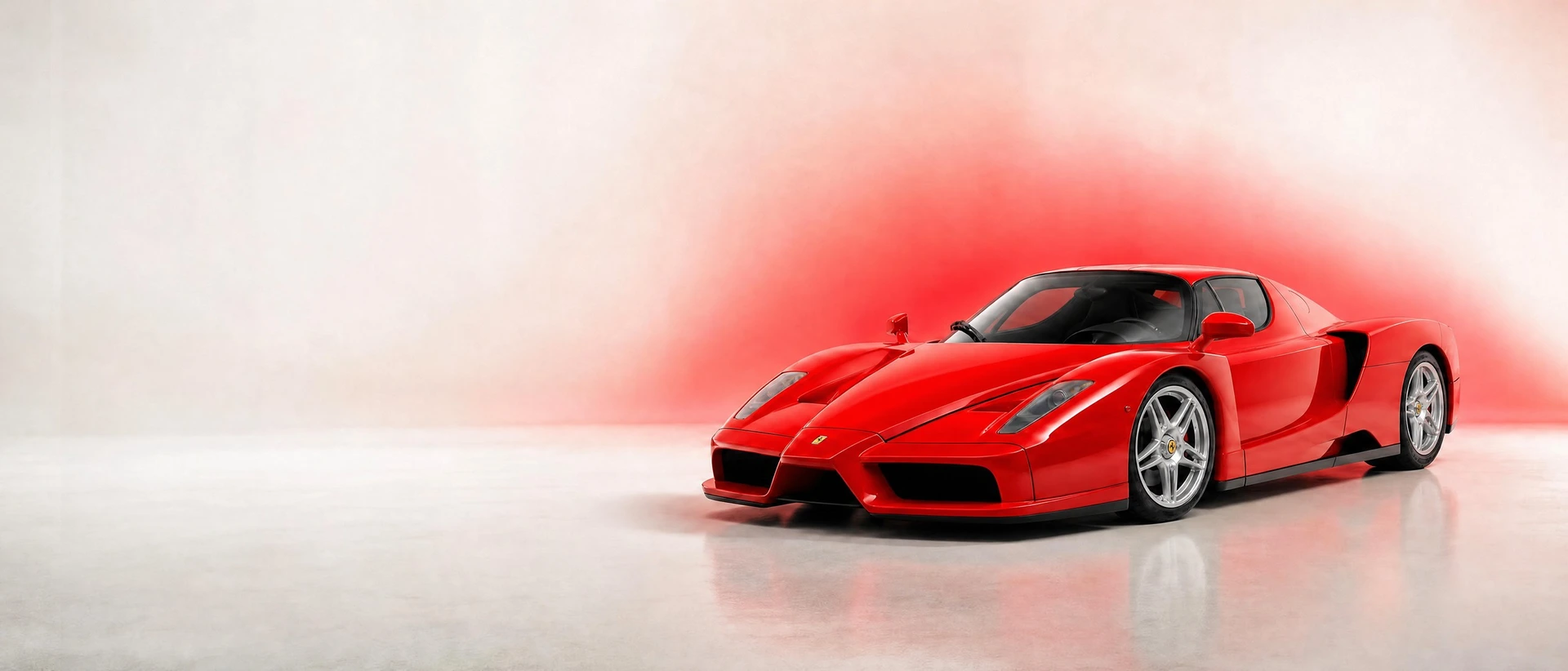 A red Ferrari Enzo, front three-quarter view on a white field with a red glow
