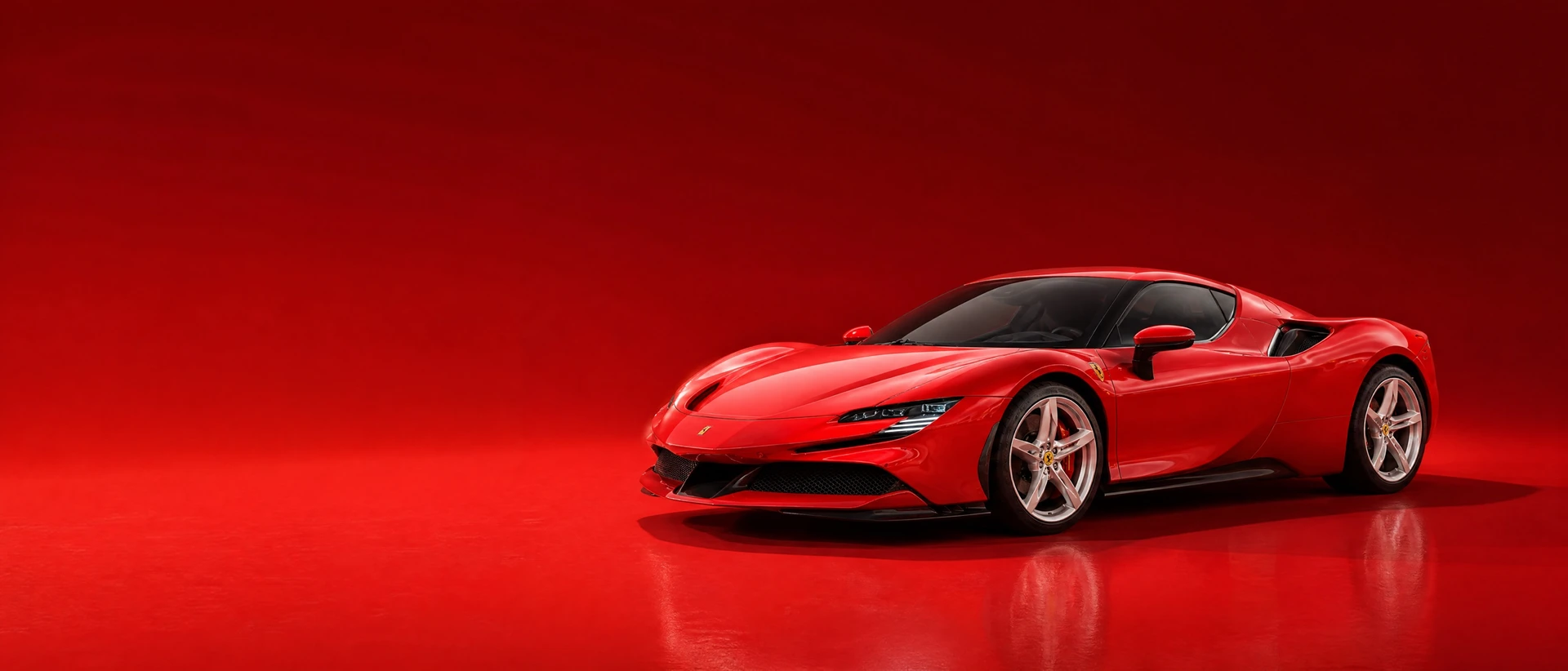 A Rosso Corsa Ferrari SF90 Stradale, front three-quarter view on a deep red field in warm daylight