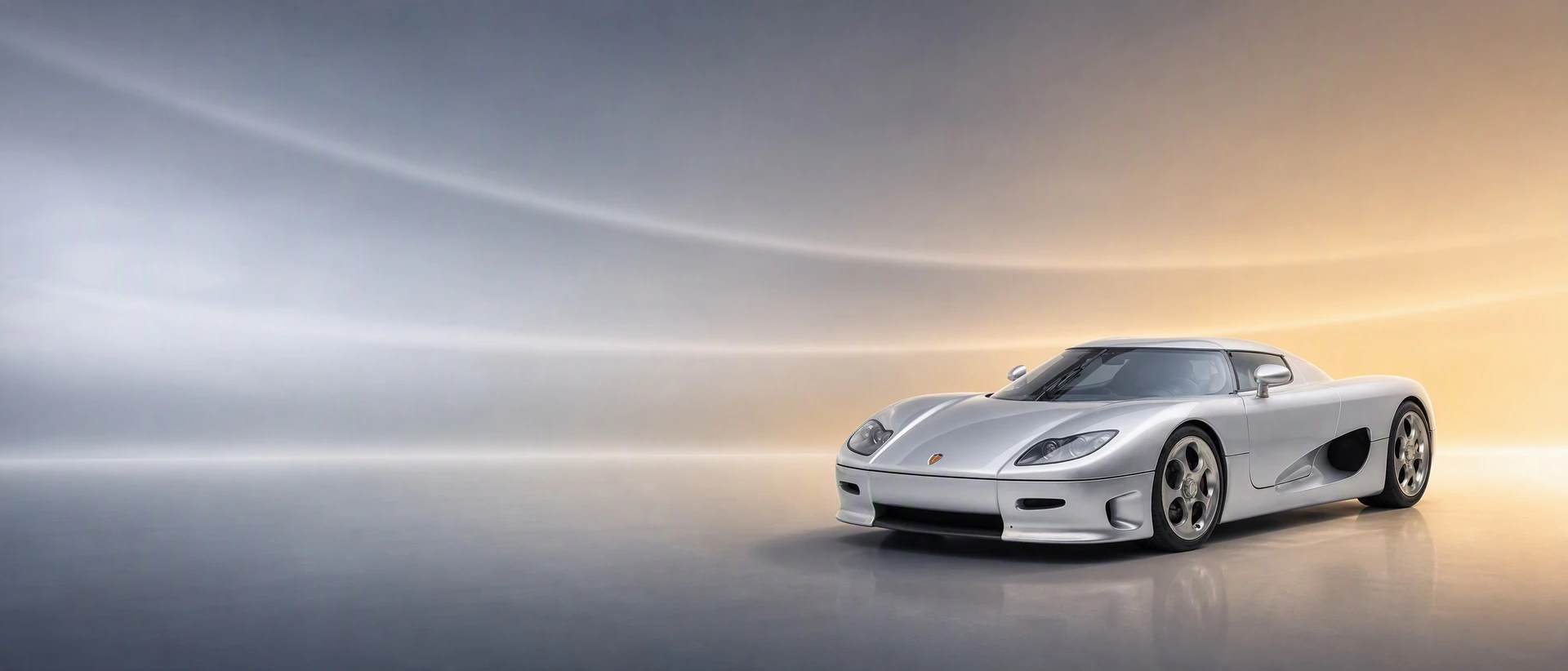 A silver Koenigsegg CC8S, front three-quarter view on a steel-blue field warming to gold