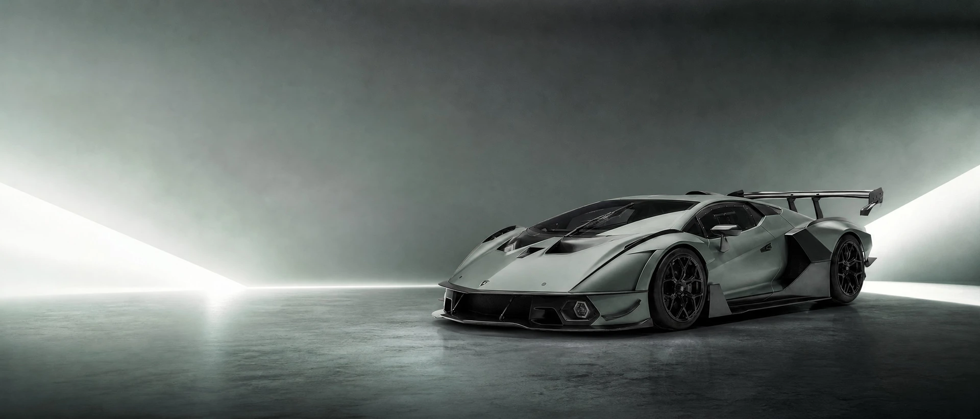 A dark grey-green Lamborghini Essenza SCV12, front three-quarter view on a graphite field with hard wedges of light