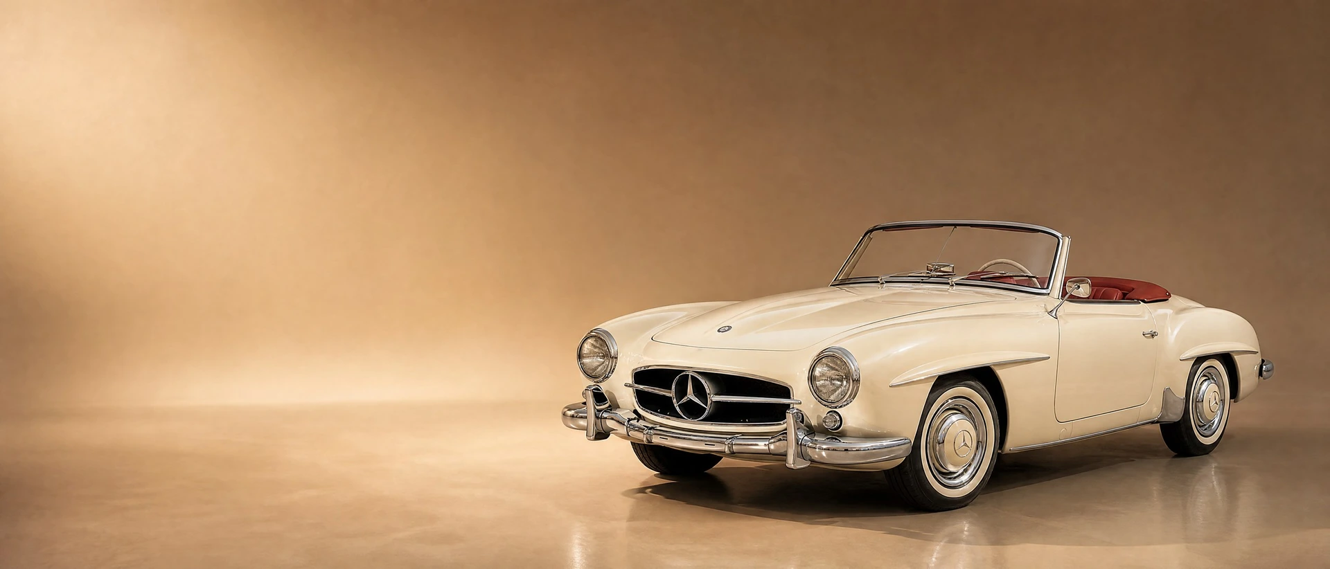 A light-ivory Mercedes-Benz 190 SL roadster with red leather, top down, on a warm champagne-taupe field in late-afternoon light