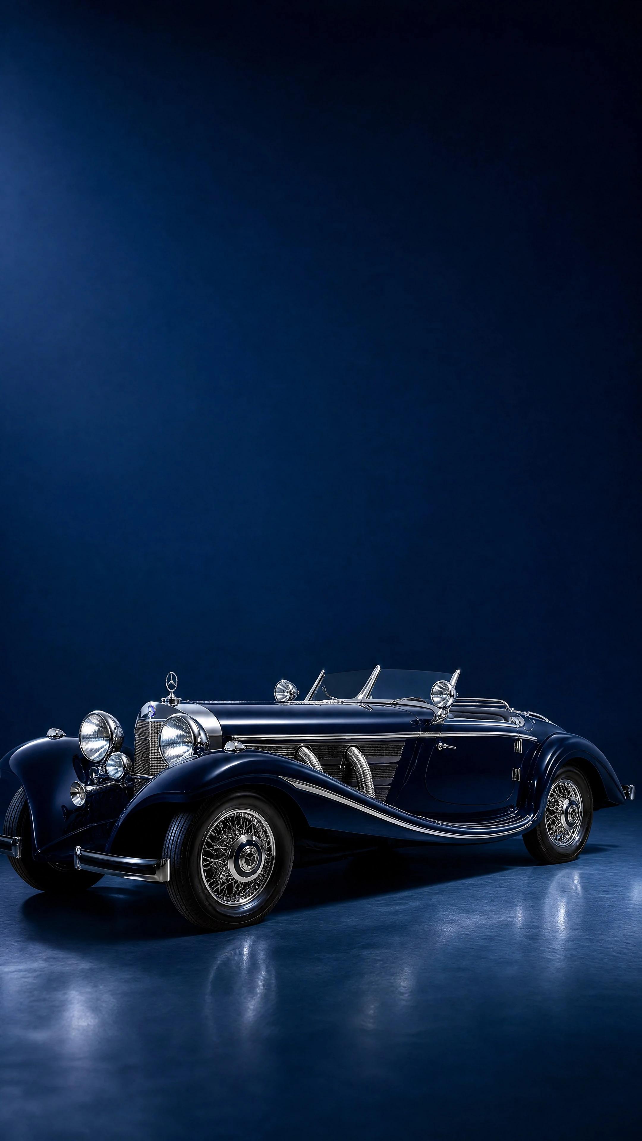 A midnight-blue Mercedes-Benz 500 K Spezial-Roadster with chrome exhaust pipes, front three-quarter view on a deep midnight-blue field in soft evening light