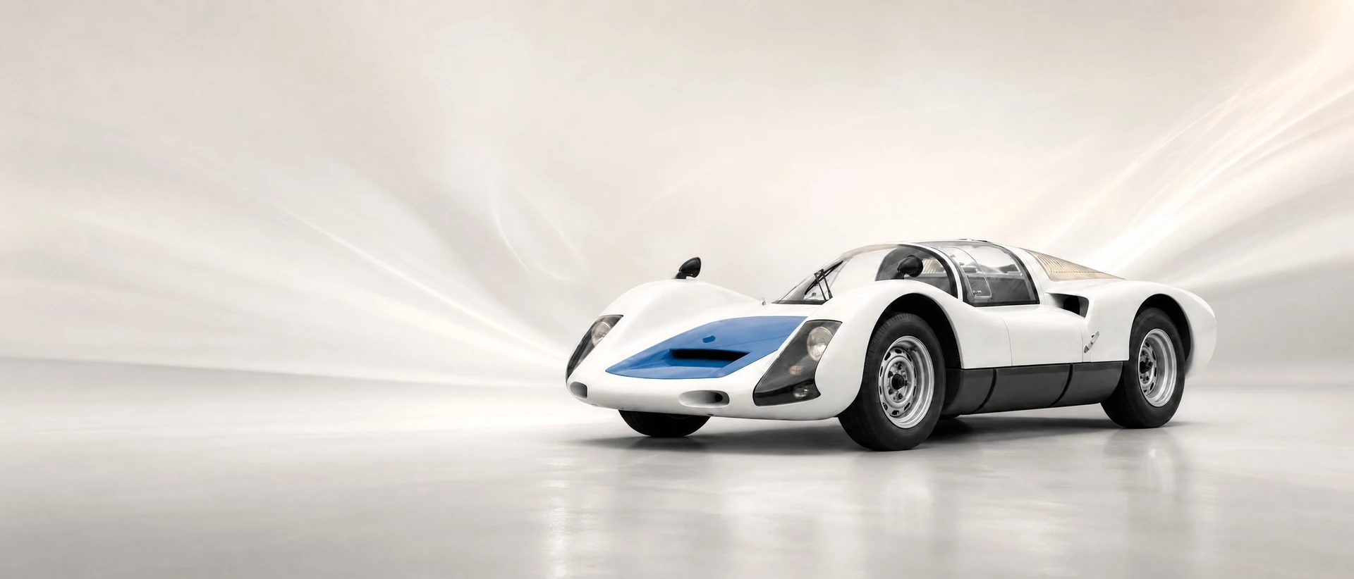A white Porsche 906 Carrera 6, front three-quarter view on a pale field with soft light trails