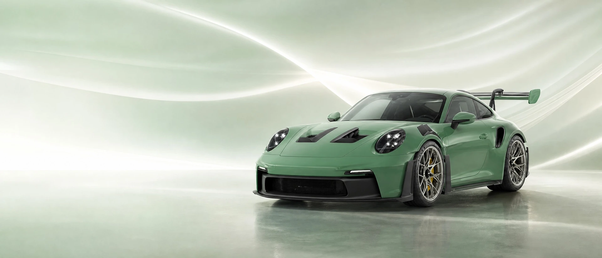 A green Porsche 992 GT3 RS, front three-quarter view on a green-white field with laminar light