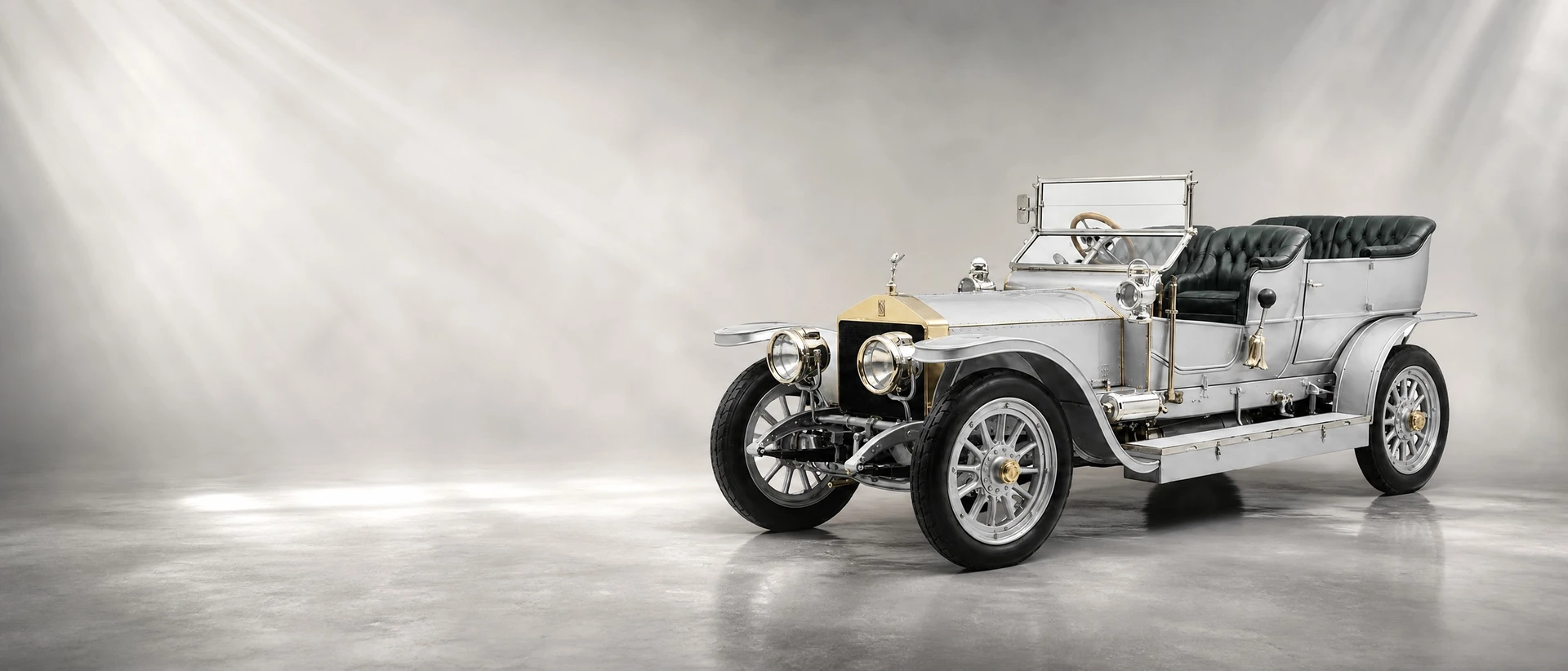 A silver Rolls-Royce Silver Ghost open tourer, front three-quarter view on a silver field with shafts of light