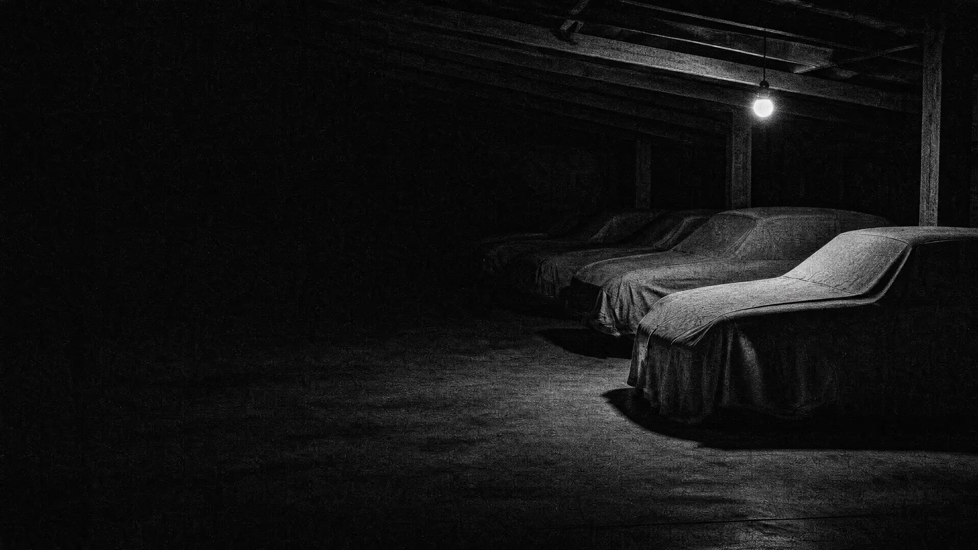 Art plate: a row of cars under dust covers in a dark garage, the nearest revealed by a single bulb