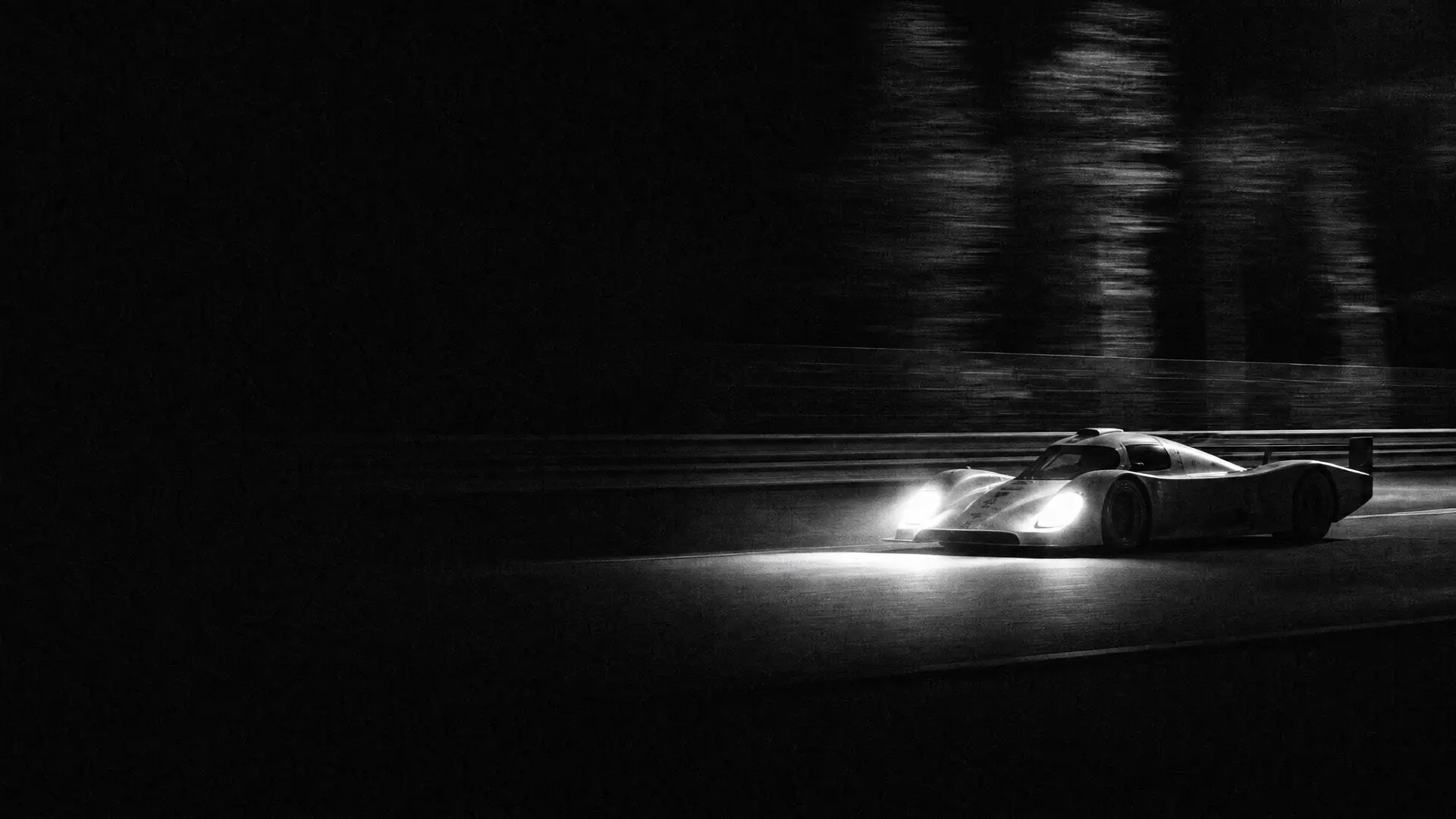 Art plate: a Porsche 956 at speed down the Mulsanne straight at night, headlights carving one cone of light