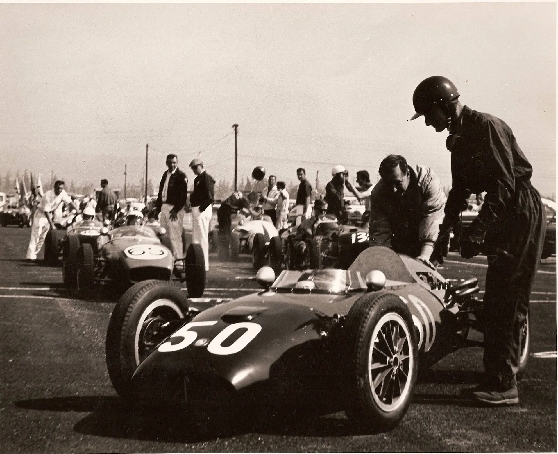 Ken Miles in helmet standing over the Dolphin Mk 2 Formula Junior on a starting grid