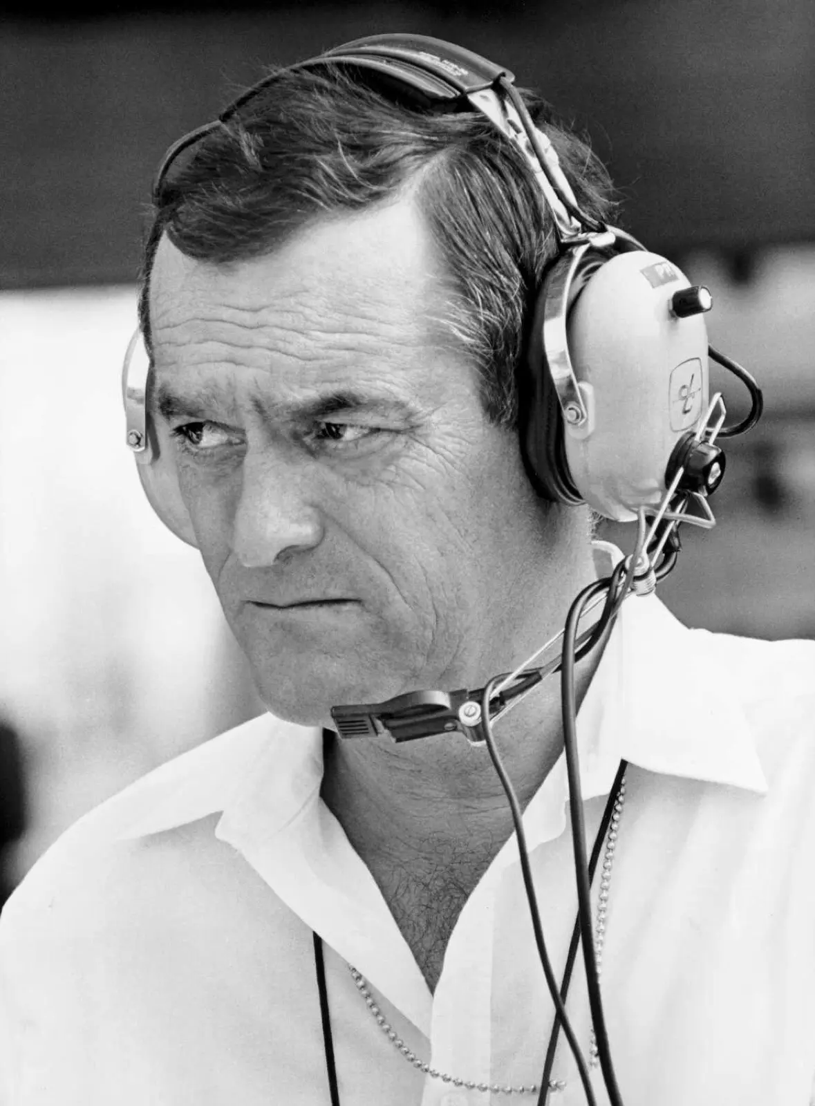 Paul Rosche trackside in BMW Motorsport attire, monitoring engine performance with a headset.